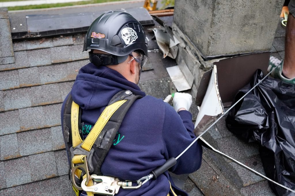 Original image of Mercer County Chimney Service tech fixing a chimney while roofside.